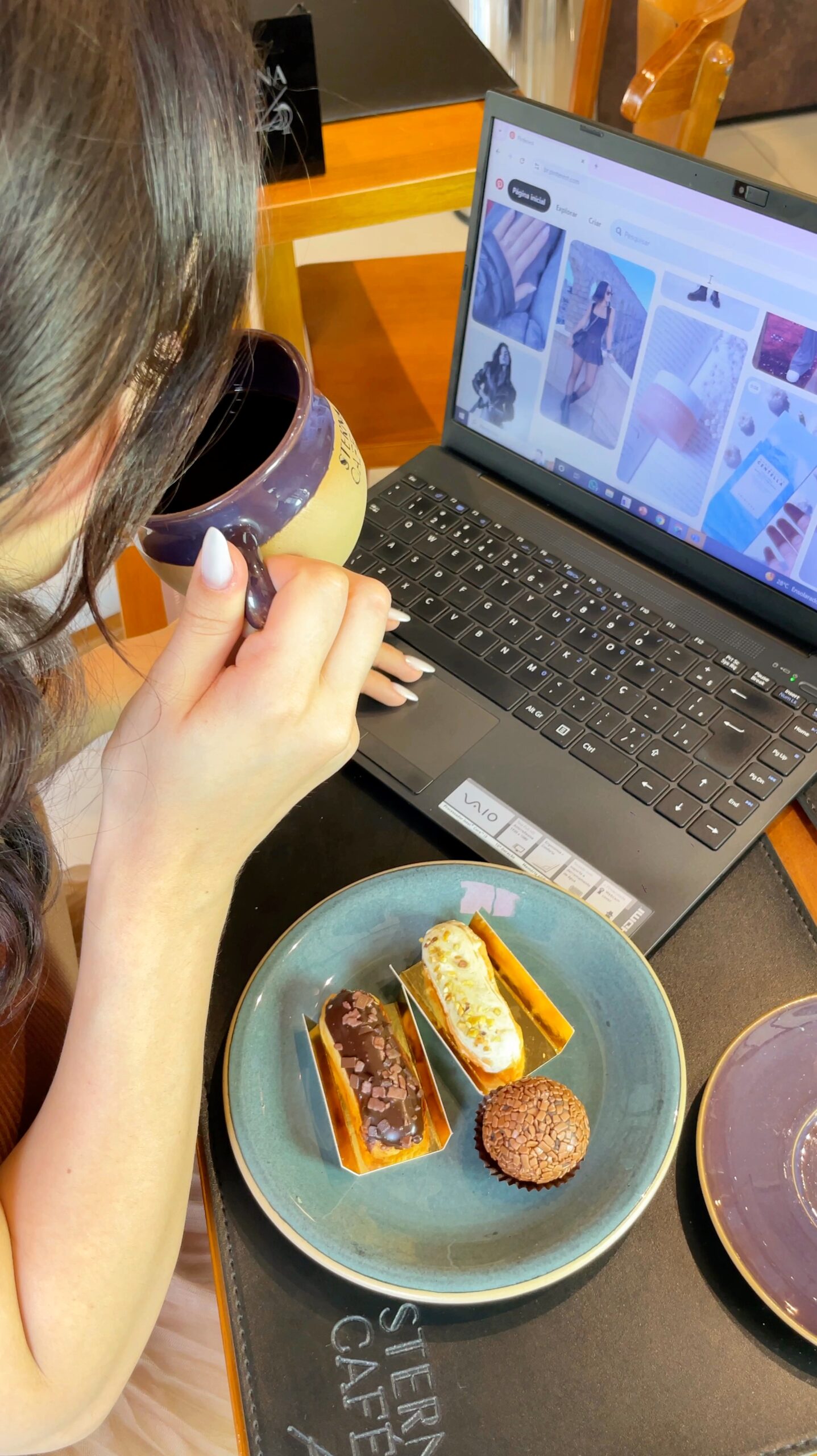 Cliente desfrutando de café e doces artesanais na Sterna Café Jardins enquanto navega no Pinterest, representando o lifestyle premium da marca.