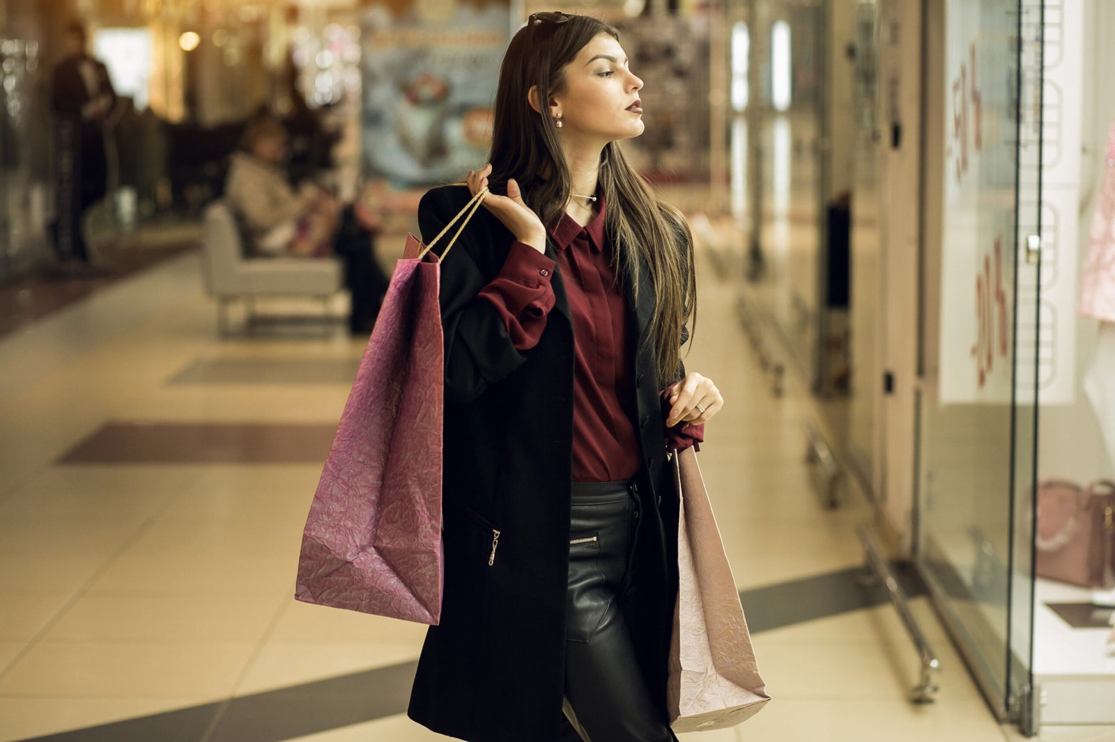 Mulher elegante segurando sacolas de compras em um shopping de luxo.