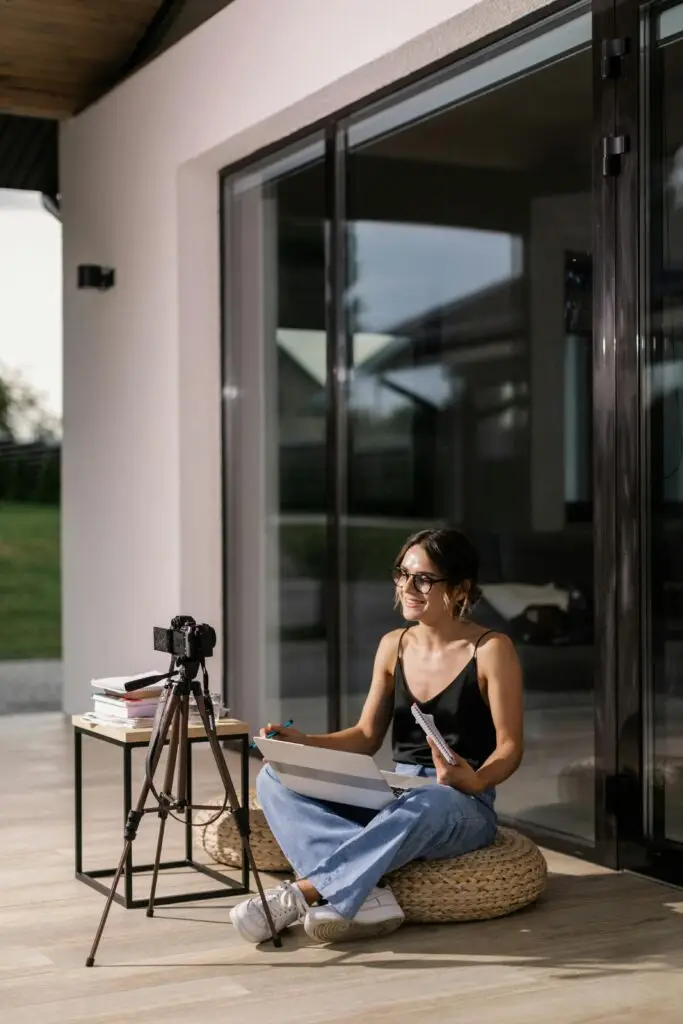Criadora de conteúdo gravando um vídeo ao ar livre, com notebook e câmera no tripé, transmitindo uma abordagem autêntica e descontraída para seu público.
