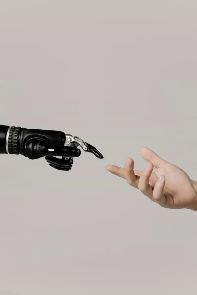 Mão humana estendendo-se para uma mão robótica, simbolizando a convergência entre tecnologia e humanidade na era digital.