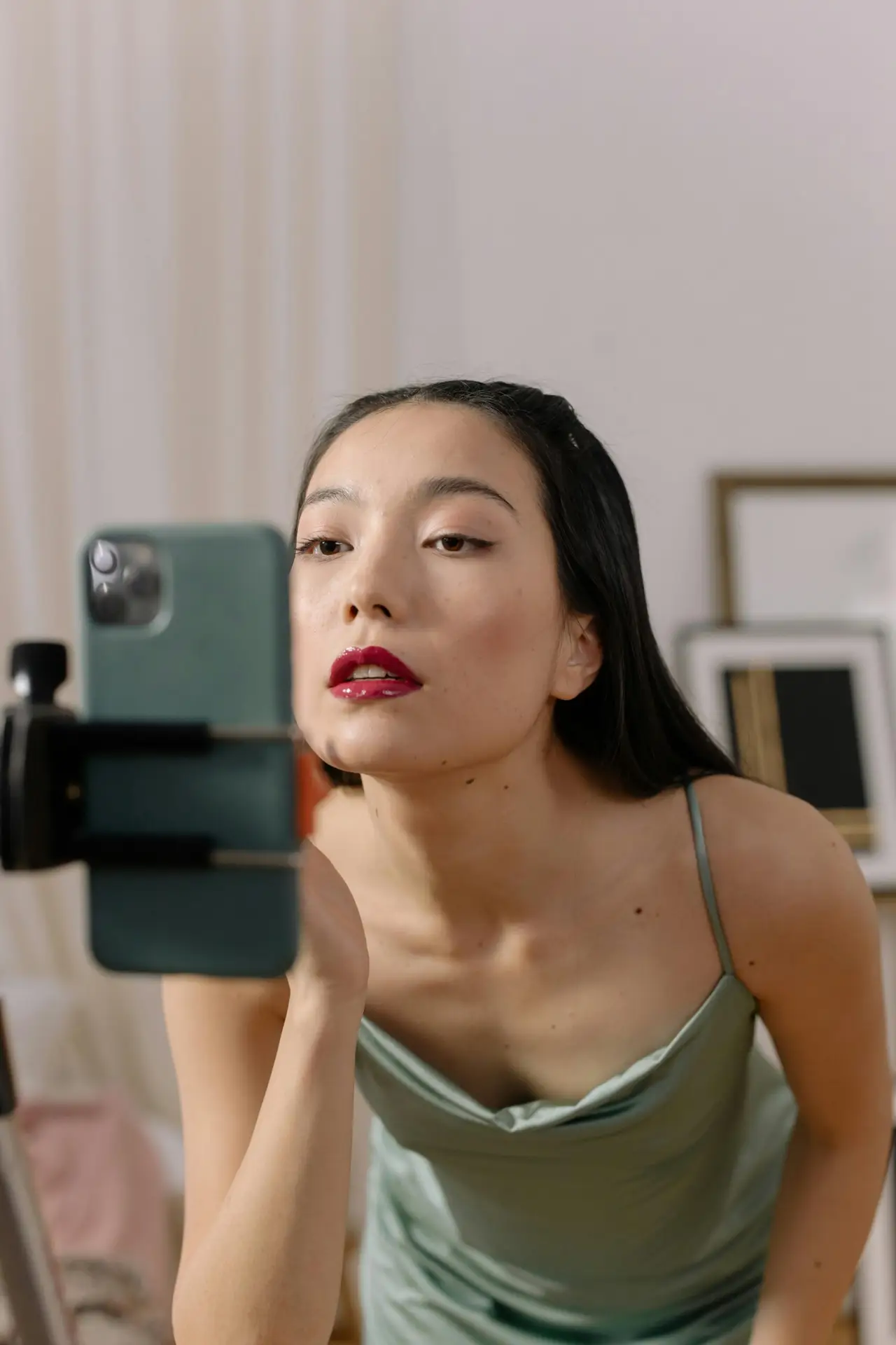 Criadora de conteúdo ajustando o enquadramento da câmera para gravação de vídeo, destacando um look sofisticado e maquiagem impecável. A imagem representa o papel estratégico do UGC Creator no marketing de luxo.